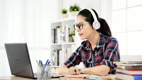 Student studying with headphones and blue light glasses